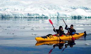 2 people kayaking next to icebergs