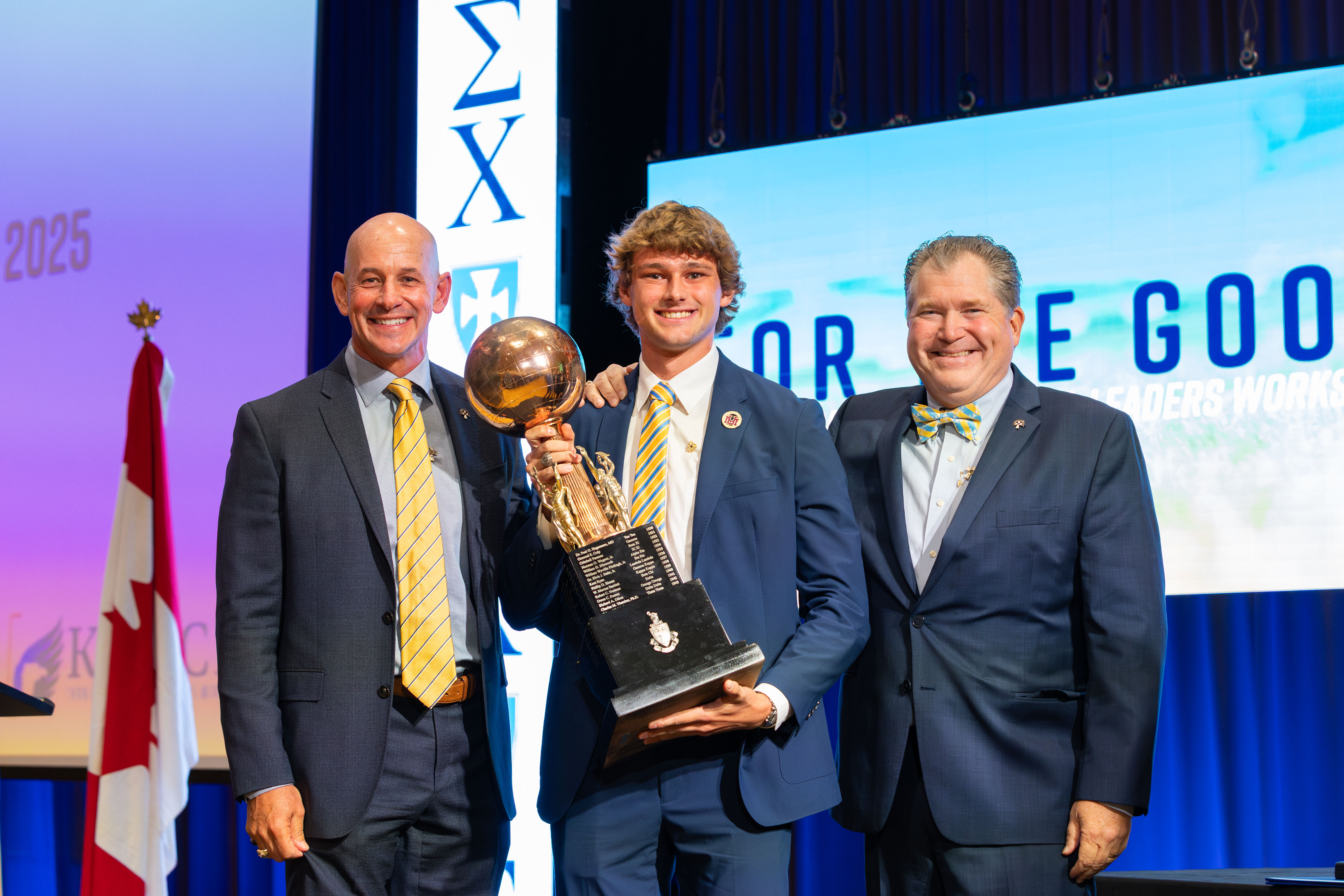 Three men on stage holding an award.
