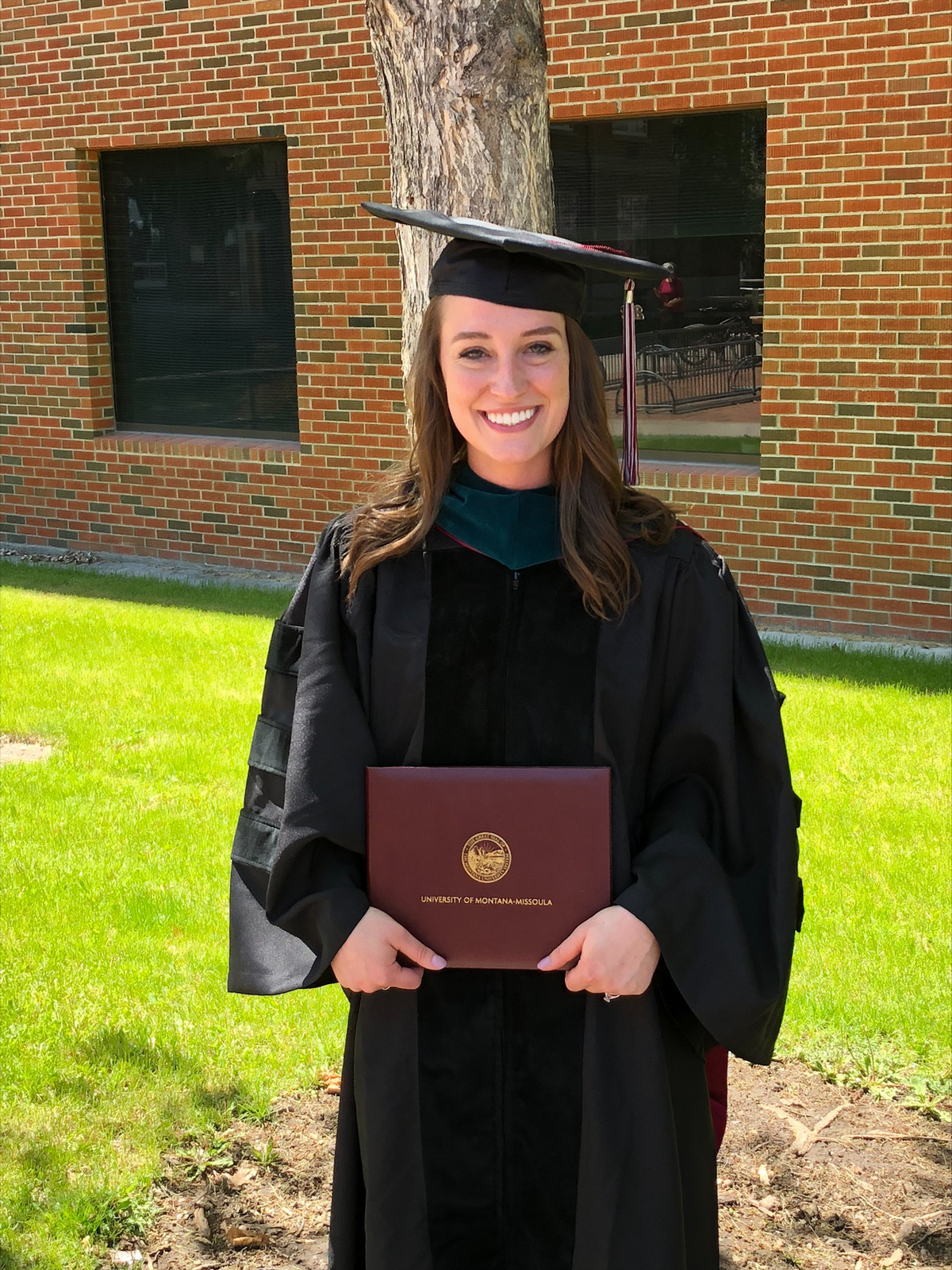 megan dalton posing with diploma in graduation garb